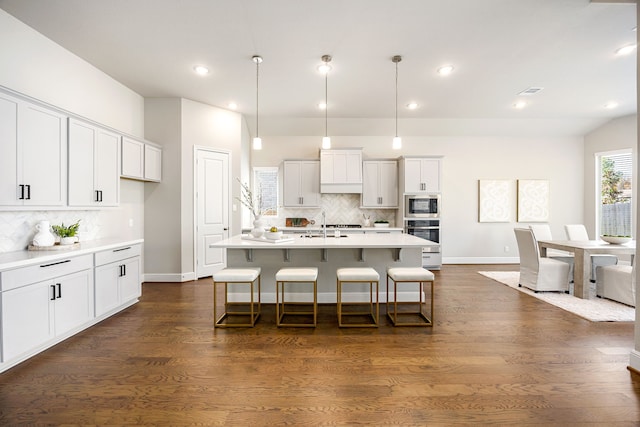 kitchen with dark wood-style floors, stainless steel appliances, light countertops, white cabinets, and a kitchen breakfast bar