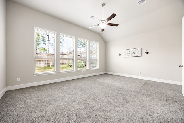 carpeted empty room with a ceiling fan, visible vents, vaulted ceiling, and baseboards