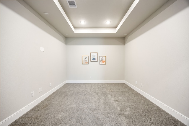 carpeted spare room with baseboards, visible vents, a raised ceiling, and recessed lighting