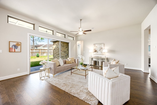 living area featuring ceiling fan, baseboards, and dark wood finished floors