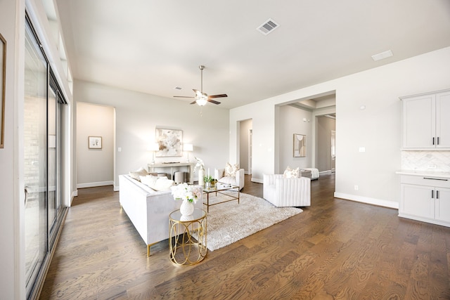 living room featuring a ceiling fan, dark wood-style flooring, visible vents, and baseboards