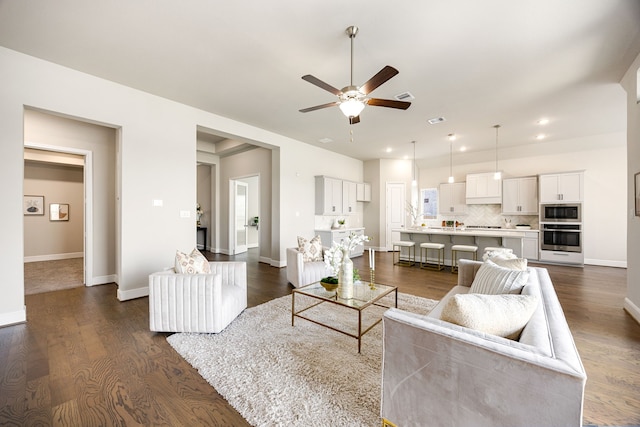 living area with ceiling fan, recessed lighting, dark wood finished floors, and baseboards