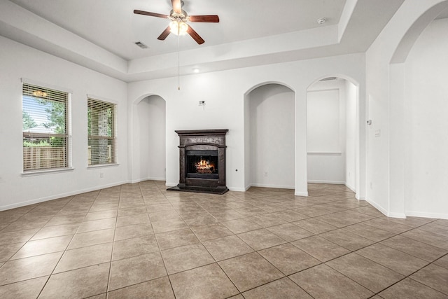 114 Kohen Ct, Montgomery, TX 77316 - unfurnished living room with a raised ceiling, a ceiling fan, light tile patterned flooring, a lit fireplace, and baseboards