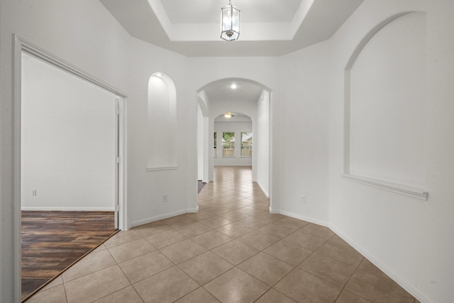 114 Kohen Ct, Montgomery, TX 77316 - hallway featuring arched walkways, a tray ceiling, tile patterned flooring, and baseboards
