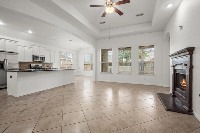 114 Kohen Ct, Montgomery, TX 77316 - unfurnished living room featuring a ceiling fan, recessed lighting, a lit fireplace, light tile patterned floors, and arched walkways