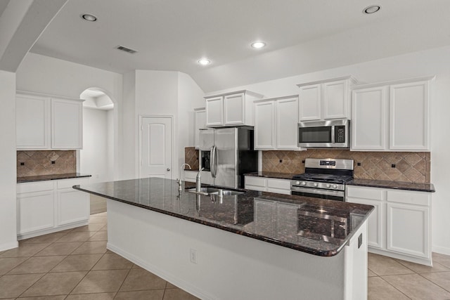 114 Kohen Ct, Montgomery, TX 77316 - kitchen featuring stainless steel appliances, light tile patterned floors, arched walkways, backsplash, and a sink