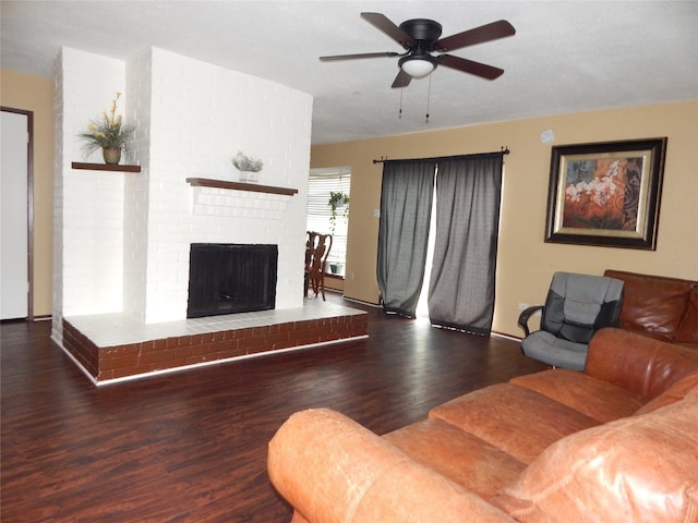 living room with dark wood-type flooring, ceiling fan, and a brick fireplace