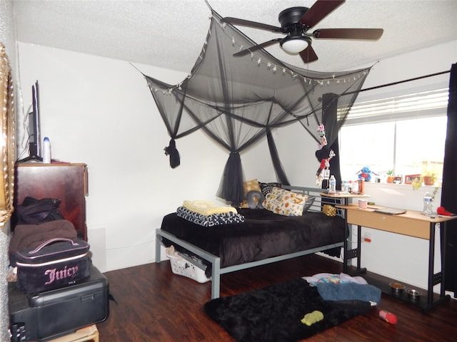 bedroom with ceiling fan, wood-type flooring, and a textured ceiling