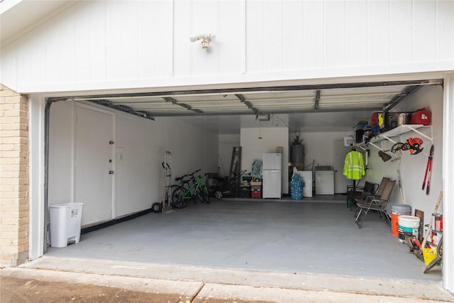 garage featuring water heater, a garage door opener, washing machine and dryer, and freestanding refrigerator