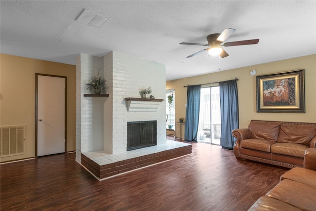 living area with a ceiling fan, wood finished floors, a fireplace, and visible vents