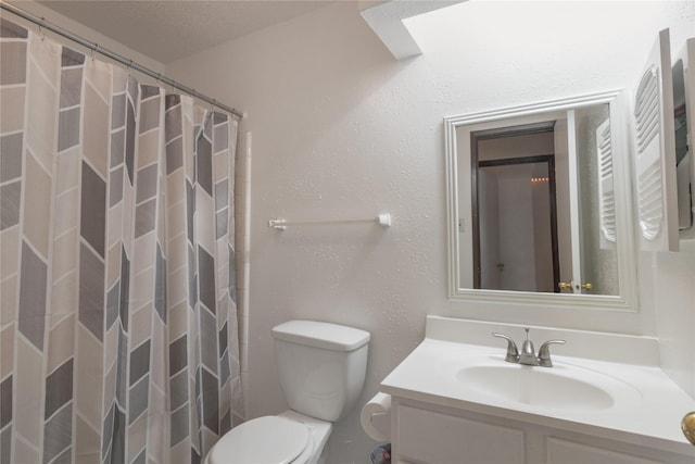 bathroom featuring toilet, vanity, a textured wall, and curtained shower