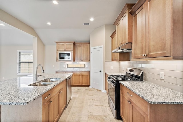 kitchen featuring appliances with stainless steel finishes, sink, a kitchen island with sink, and light stone counters