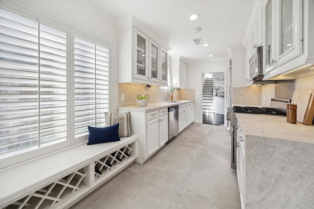 kitchen featuring white cabinetry, backsplash, crown molding, and appliances with stainless steel finishes