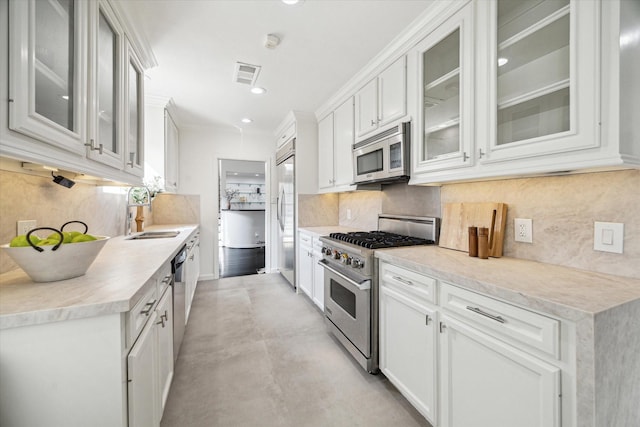 kitchen featuring backsplash, high quality appliances, sink, and white cabinets