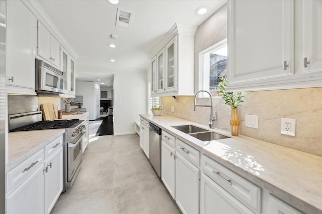 kitchen with stainless steel appliances, sink, white cabinetry, tasteful backsplash, and a healthy amount of sunlight