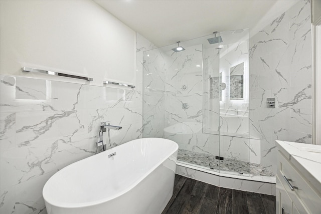 bathroom featuring plus walk in shower, hardwood / wood-style floors, vanity, and tile walls