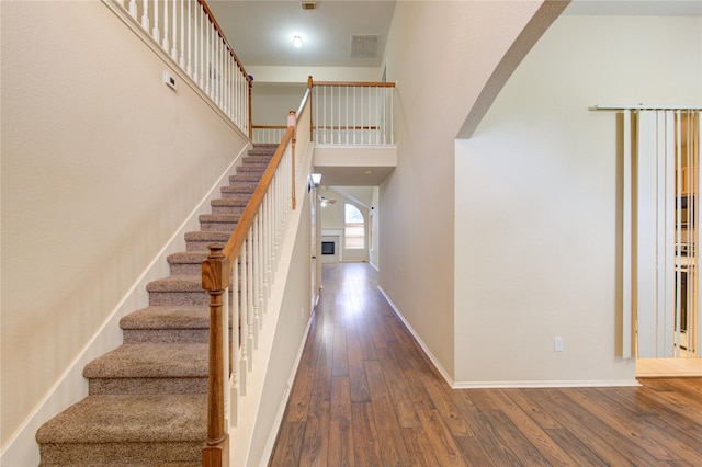 staircase with hardwood / wood-style flooring and a high ceiling