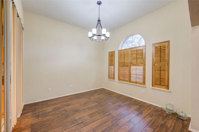 spare room featuring dark hardwood / wood-style floors and an inviting chandelier