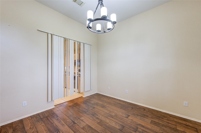 spare room with an inviting chandelier and dark hardwood / wood-style floors