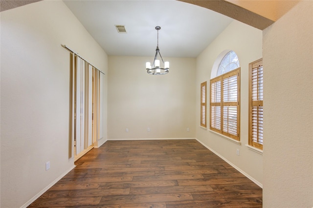 unfurnished dining area featuring a notable chandelier and dark wood-type flooring