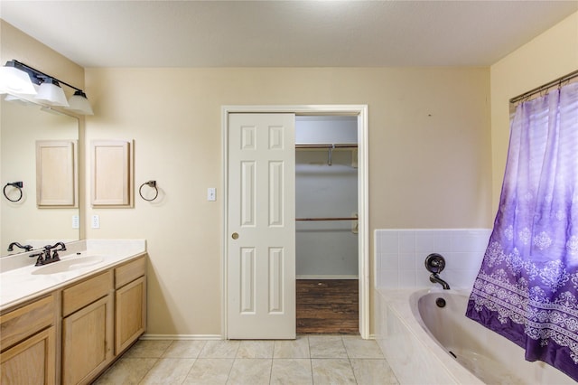 bathroom with vanity, a relaxing tiled tub, and tile patterned floors