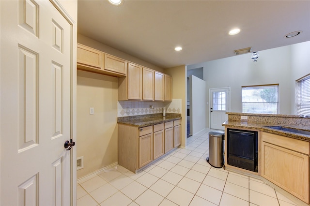 kitchen with sink, light tile patterned floors, light brown cabinetry, and decorative backsplash