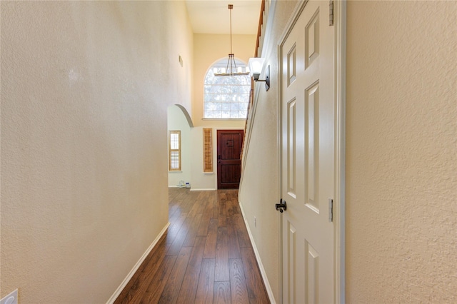 corridor featuring an inviting chandelier, dark hardwood / wood-style flooring, and a high ceiling