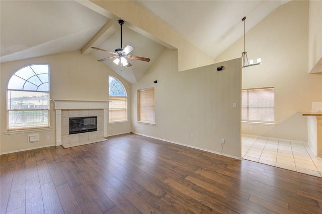 unfurnished living room featuring beam ceiling, a tile fireplace, dark hardwood / wood-style floors, and ceiling fan