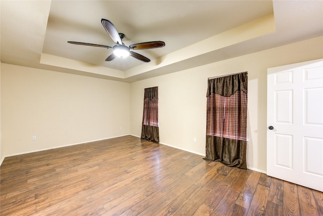 unfurnished bedroom with wood-type flooring, a raised ceiling, and ceiling fan