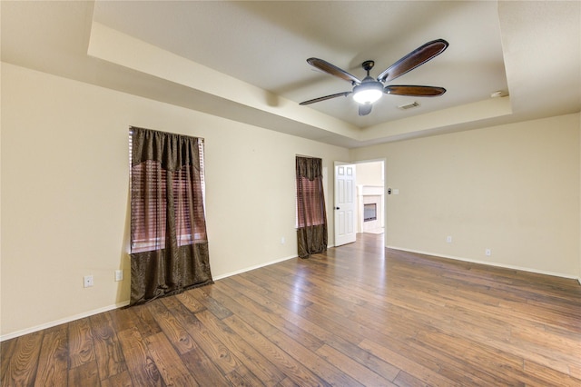 unfurnished room with hardwood / wood-style floors, ceiling fan, and a tray ceiling