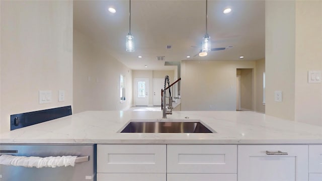 kitchen with hanging light fixtures, stainless steel dishwasher, white cabinetry, and light stone countertops