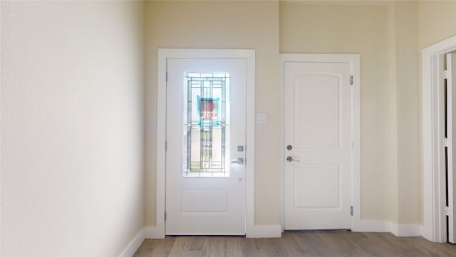 doorway with light wood finished floors and baseboards