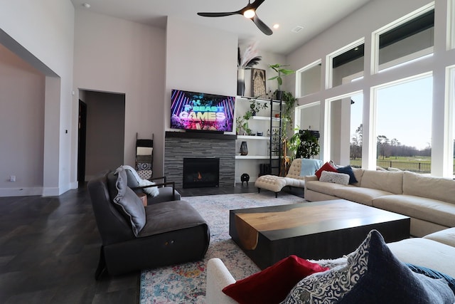 living room with ceiling fan, a high ceiling, a fireplace, and baseboards