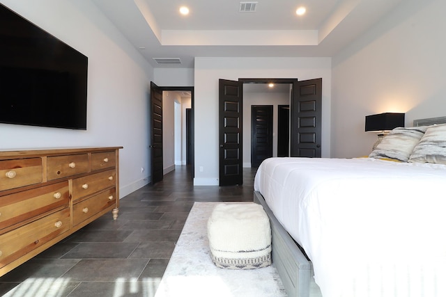 bedroom with a tray ceiling, visible vents, and baseboards