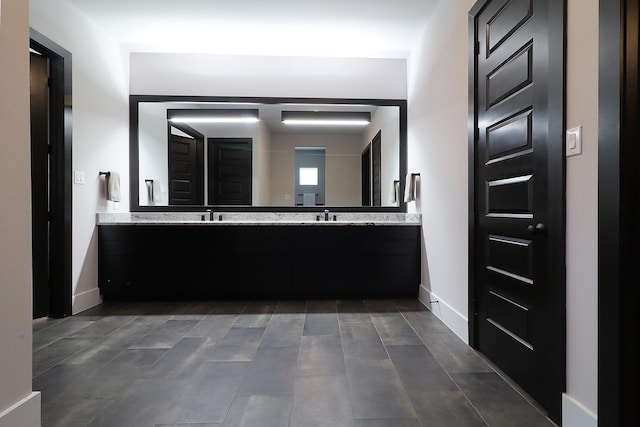 full bath featuring double vanity, baseboards, and a sink