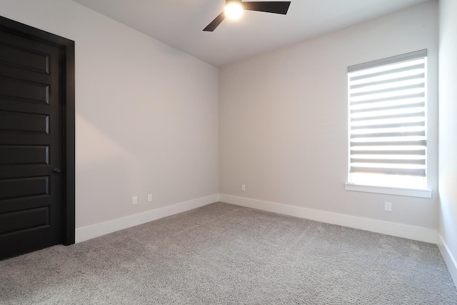 carpeted spare room with a ceiling fan and baseboards