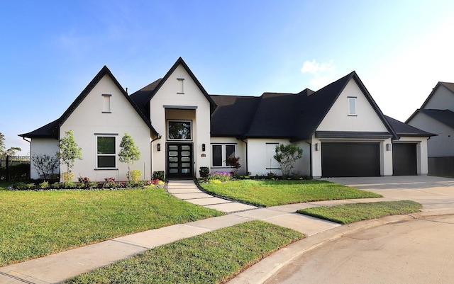 view of front facade with french doors, driveway, stucco siding, and a front lawn