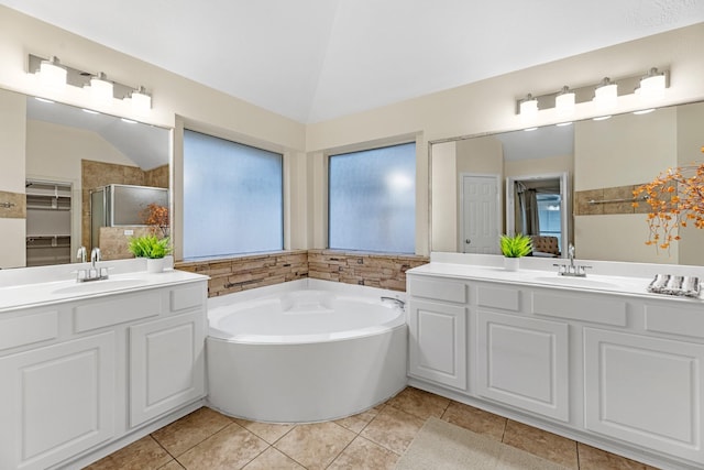 full bath with vaulted ceiling, a sink, a bath, and tile patterned floors