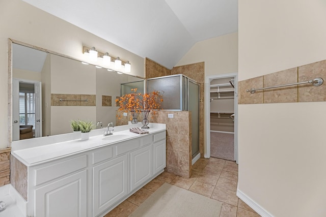 bathroom featuring lofted ceiling, vanity, a spacious closet, tile patterned floors, and a stall shower