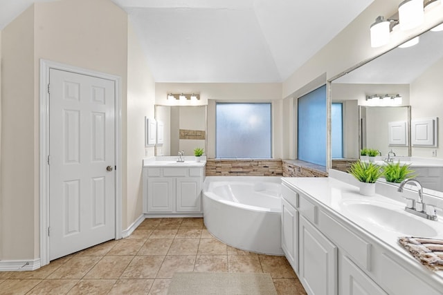 bathroom with tile patterned flooring, vaulted ceiling, two vanities, and a sink