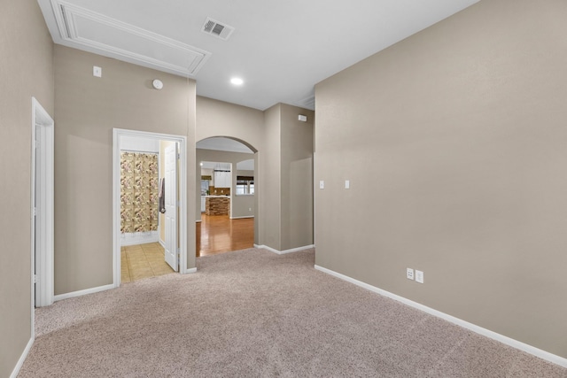 spare room with light carpet, attic access, visible vents, and baseboards