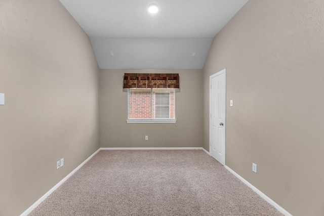 empty room with carpet, vaulted ceiling, and baseboards