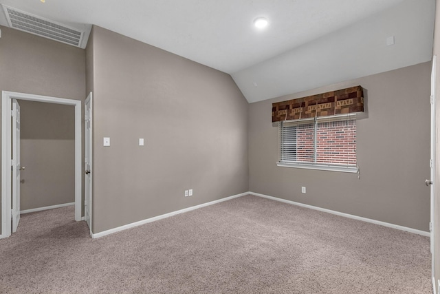 carpeted empty room with baseboards, visible vents, and vaulted ceiling