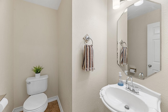 bathroom featuring toilet, baseboards, a sink, and tile patterned floors