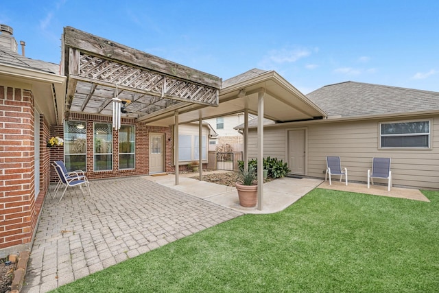 rear view of property with fence, a yard, a patio area, a pergola, and brick siding