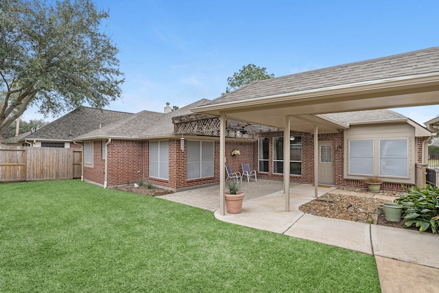 back of property featuring a patio area, roof with shingles, a lawn, and brick siding