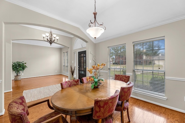 dining room with arched walkways, a notable chandelier, wood finished floors, baseboards, and ornamental molding