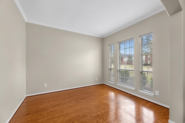 empty room featuring arched walkways, crown molding, baseboards, and wood finished floors