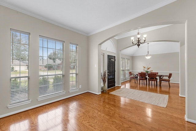 foyer featuring ornamental molding, a notable chandelier, baseboards, and wood finished floors