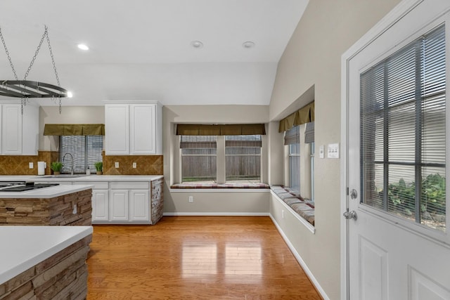 kitchen featuring decorative backsplash, white cabinetry, light countertops, and a sink